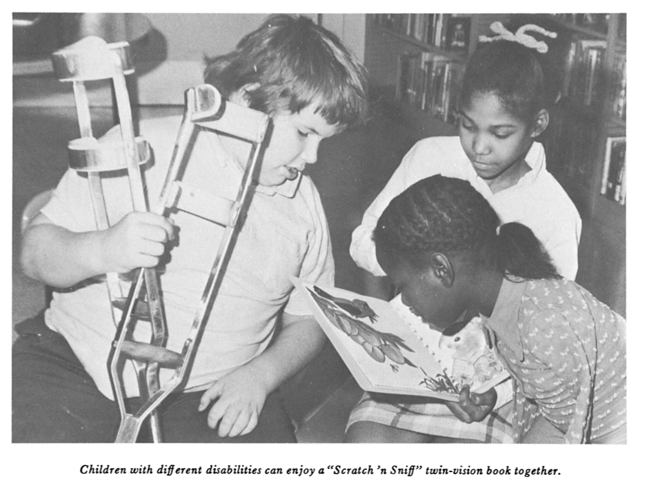 Three children with different disabilities read a Scratch 'n Sniff Twin Vision book together