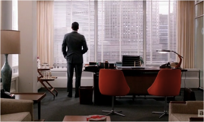 Don standing in his slick modernist office staring out at a sea of skyscrapers 